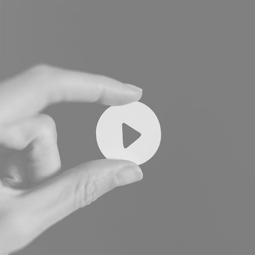 Hand holding a play button - and arrow pointing to the right.